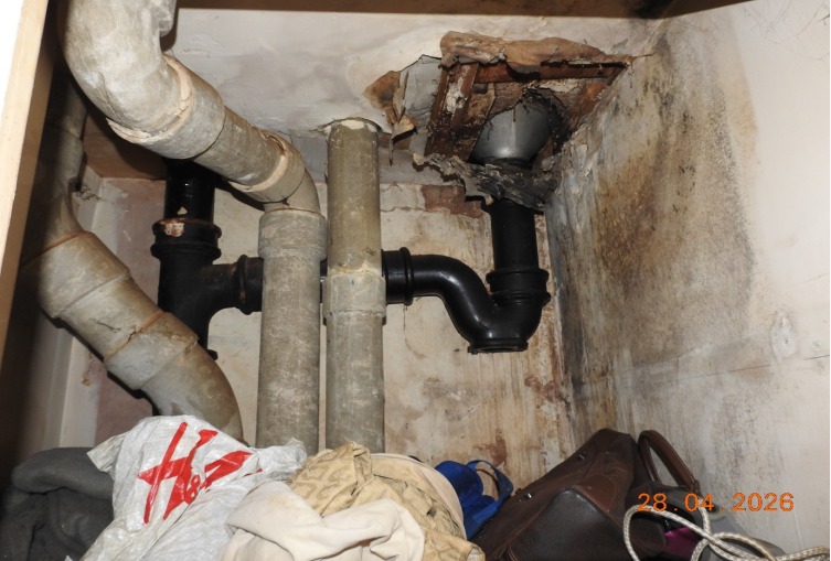 Water damaged collapsed ceiling plaster, asbestos cement pipes in kitchen cupboard.